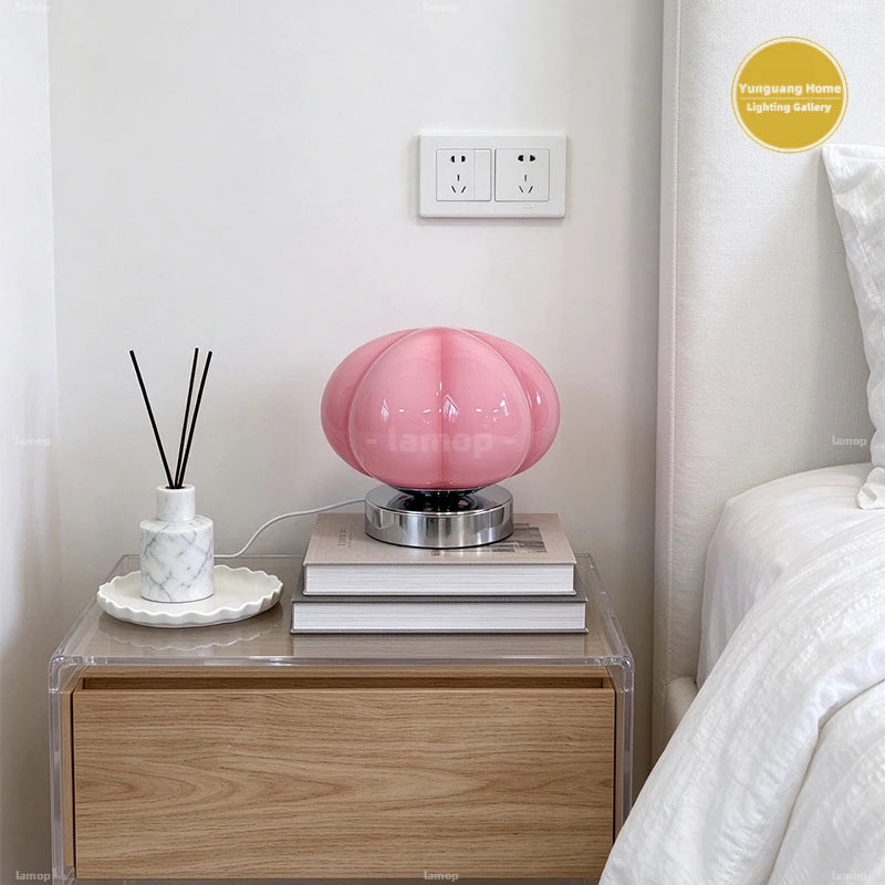 Lampe citrouille en verre rose sur une table de chevet
