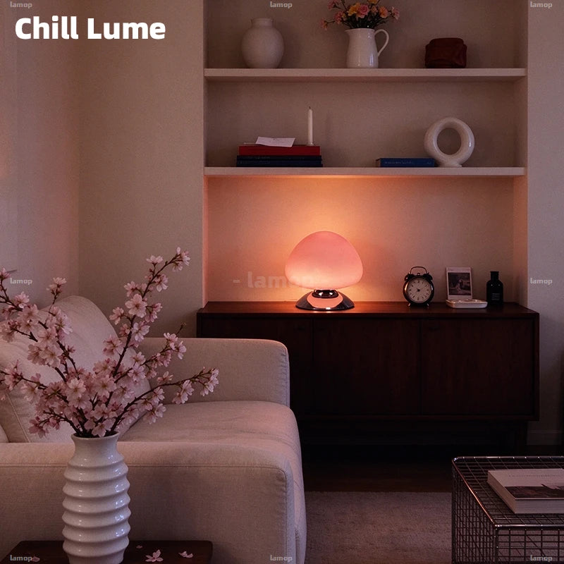 Lampe champignon en verre rose allumée dans un salon