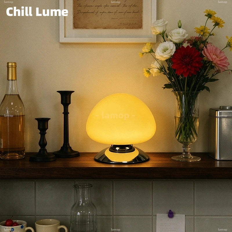 Lampe champignon en verre jaune allumée sur une étagère