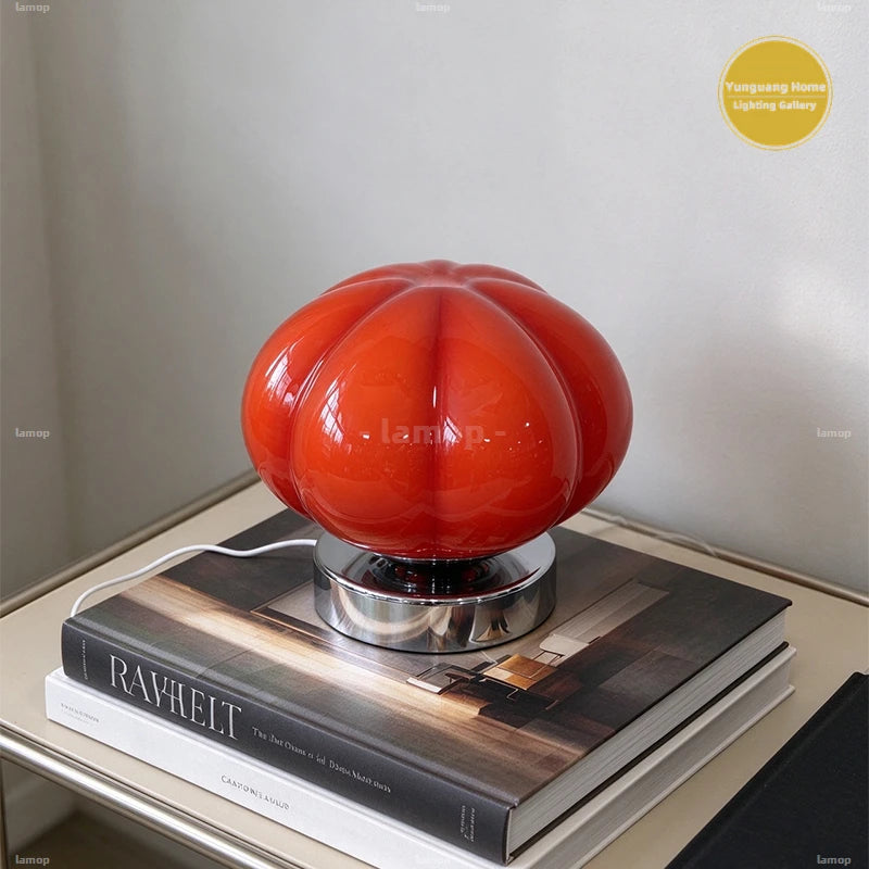 Lampe citrouille en verre rouge sur des livres